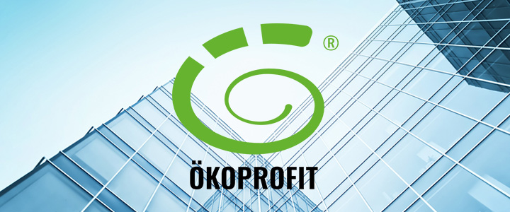 Logo ÖKOPROFIT auf einer Häuserfasade aus Glas.
